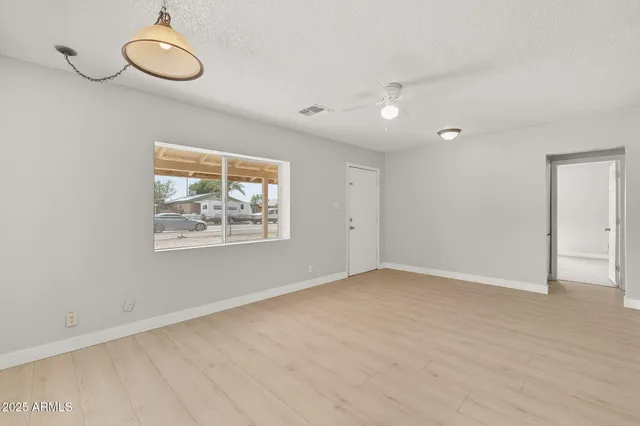 an empty room with wooden floor and windows