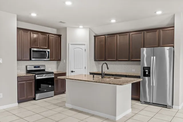 a kitchen with stainless steel appliances granite countertop a refrigerator sink and microwave