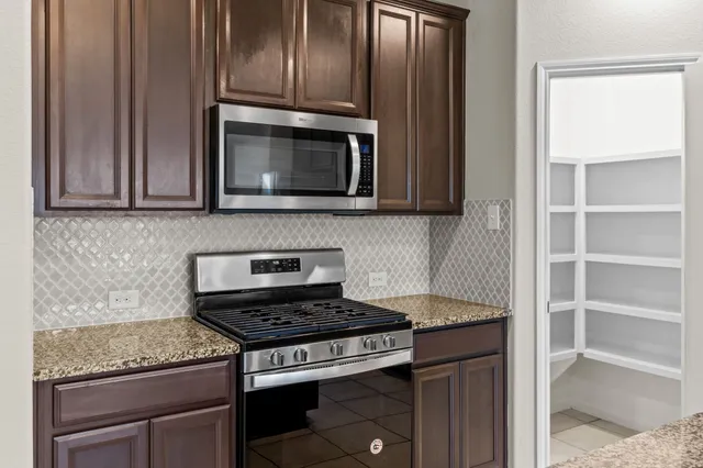 a kitchen with granite countertop cabinets stove top oven and microwave