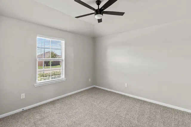 an empty room with a window and a fan