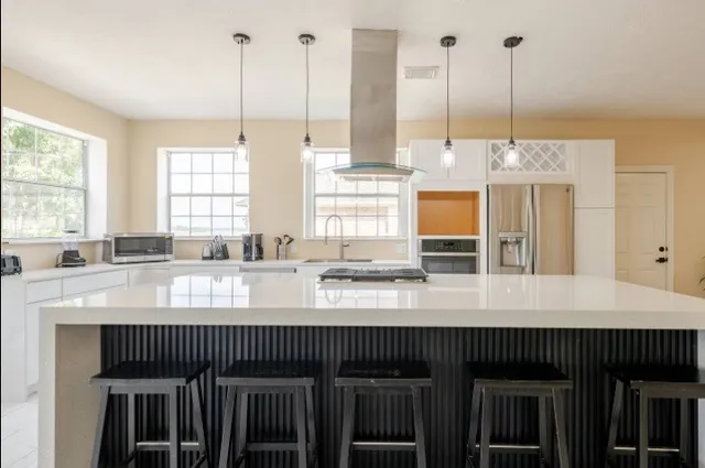 a kitchen with kitchen island granite countertop a stove a sink and white cabinets