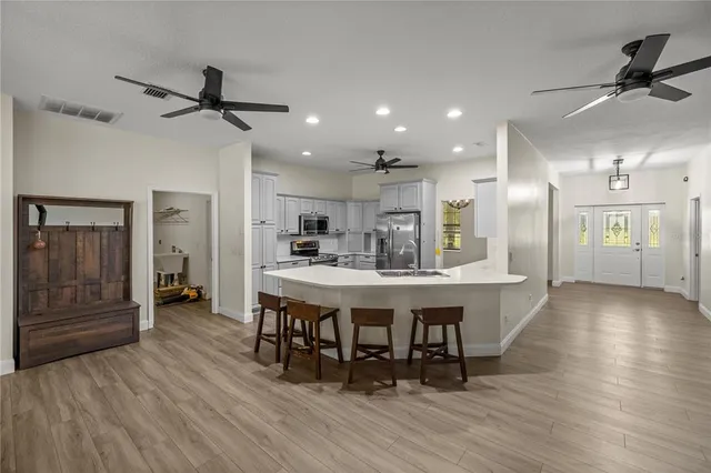 a kitchen with stainless steel appliances a dining table chairs and wooden floor