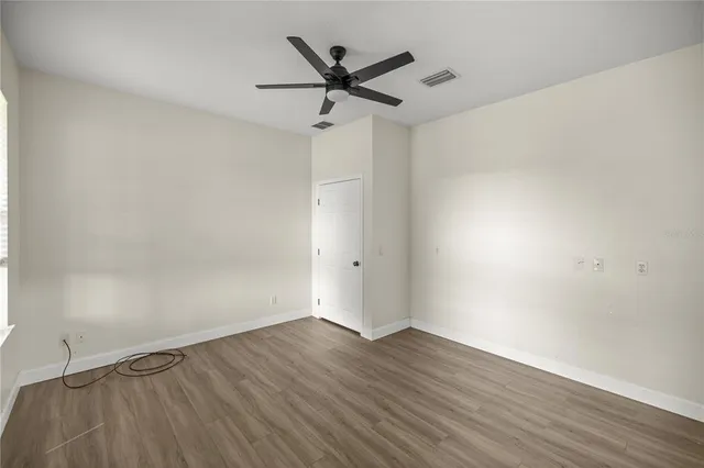 an empty room with wooden floor ceiling fan and windows