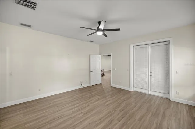 a view of empty room with wooden floor and fan