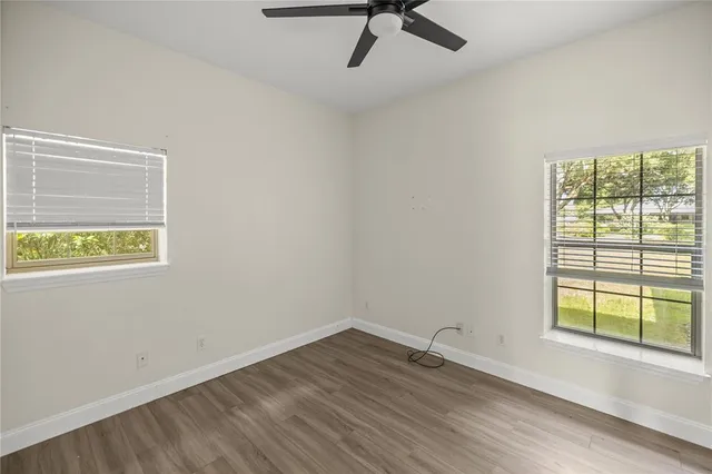 a view of room with hardwood floor and a ceiling fan