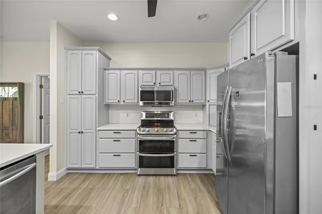 a kitchen with white cabinets and stainless steel appliances