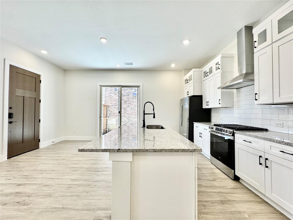 8513 Shorehan Road The Colony, TX 75056 - Photo 14 of 25 Kitchen featuring appliances with stainless steel finishes, wall chimney range hood, a sink, light wood finished floors, and recessed lighting