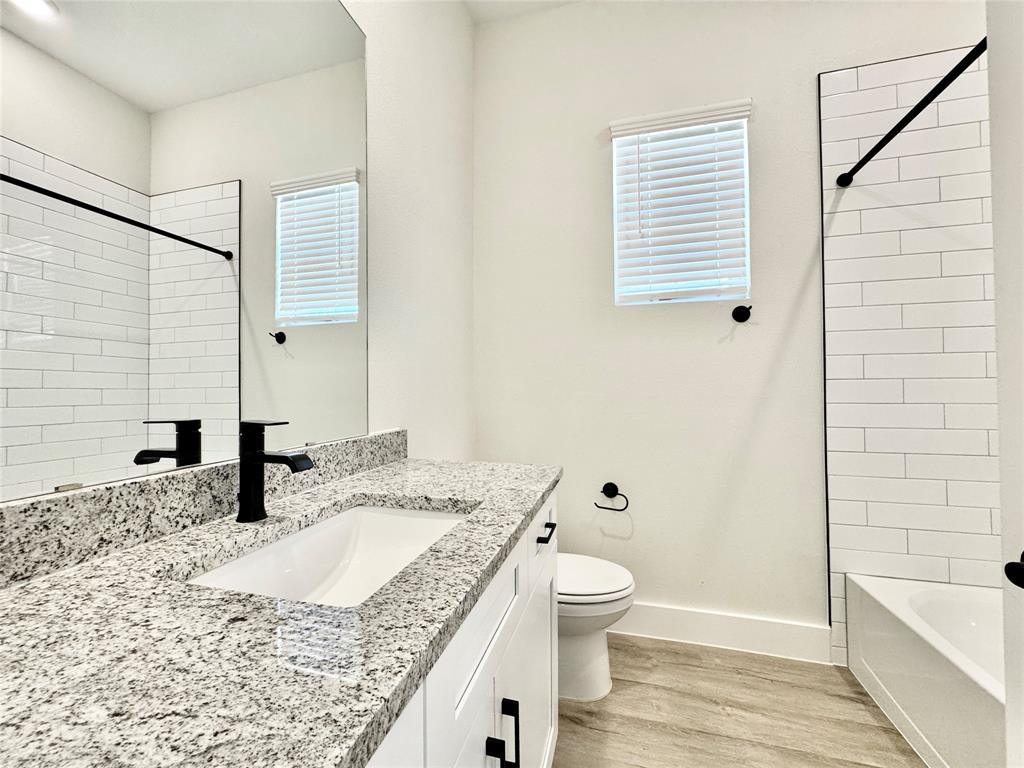 8513 Shorehan Road The Colony, TX 75056 - Photo 16 of 25 Full bath with wood finished floors, baseboards, toilet, vanity, and shower / bathtub combination