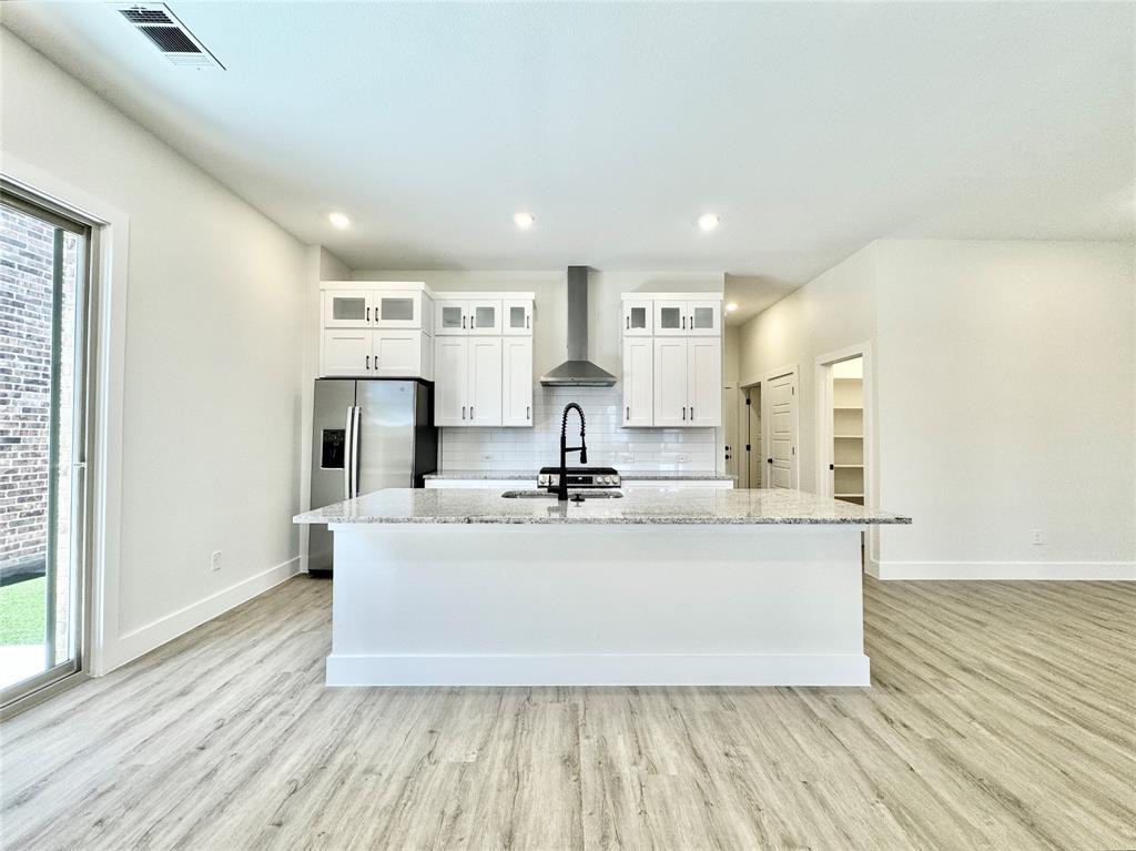 8513 Shorehan Road The Colony, TX 75056 - Photo 4 of 25 Kitchen with wall chimney exhaust hood, stainless steel refrigerator with ice dispenser, baseboards, light wood-style floors, and recessed lighting