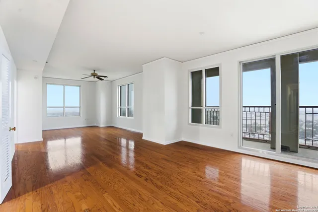a view of an empty room with glass door and wooden floor