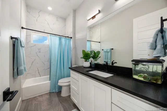 a bathroom with a granite countertop sink a toilet and bathtub