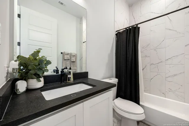 a bathroom with a granite countertop sink a toilet and shower