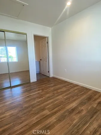 an empty room with wooden floor and mirror