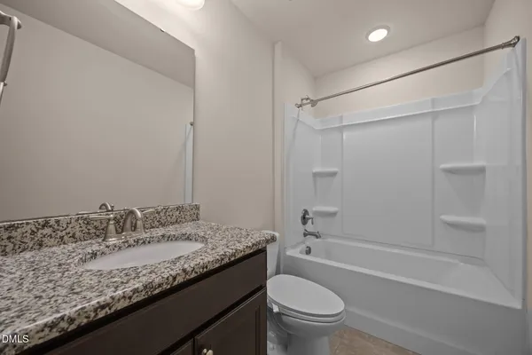 a bathroom with a granite countertop sink a toilet and shower