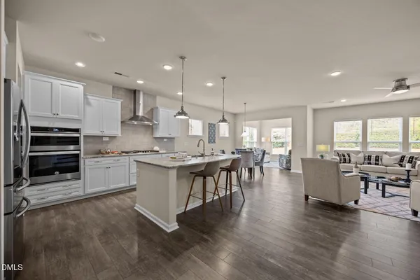 a large white kitchen with lots of counter space a sink appliances and dining table