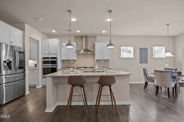 a kitchen with kitchen island stainless steel appliances a dining table and chairs
