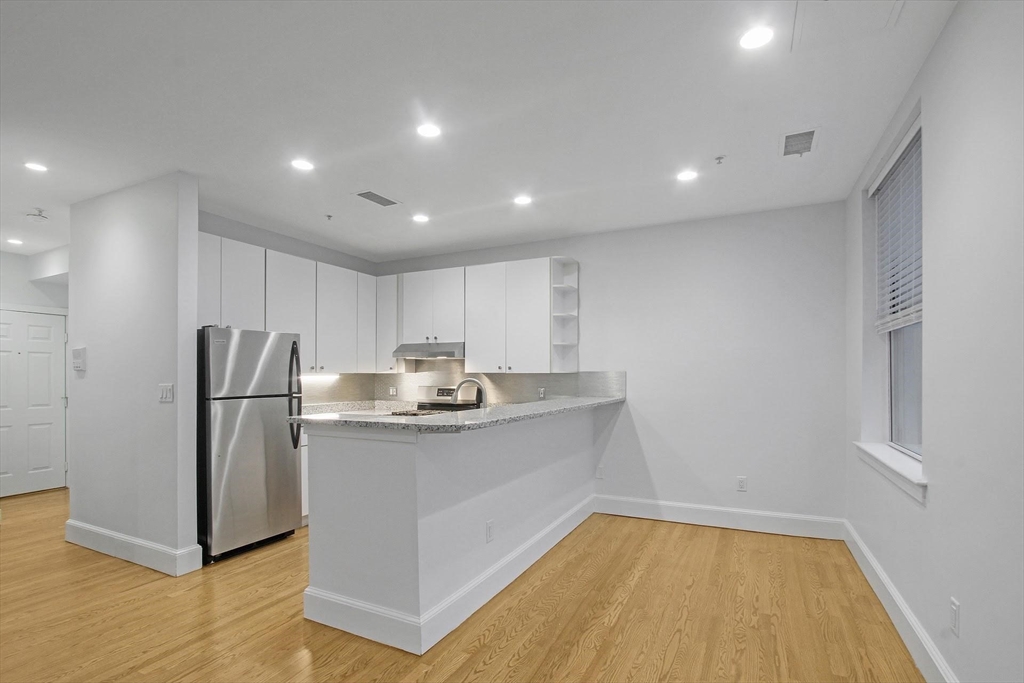 140 Boylston Street, Unit 10 Boston, MA 02116 - Photo 6 of 14 a kitchen with kitchen island a sink and a refrigerator