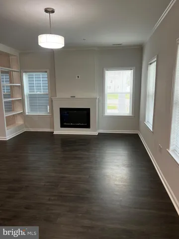 a view of wooden floor fire place and windows in an empty room