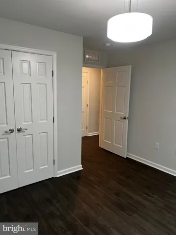 an empty room with wooden floor cabinet and windows