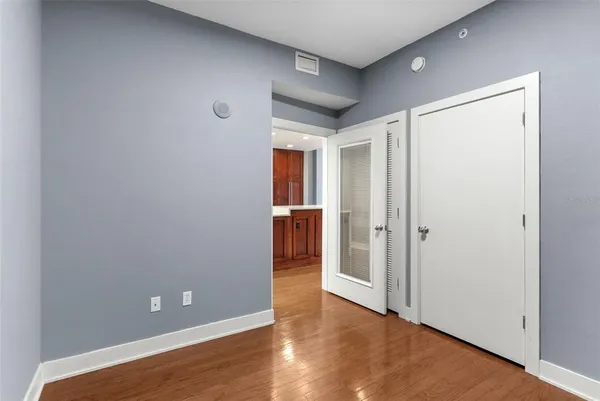 a view of an empty room with wooden floor and a bathroom