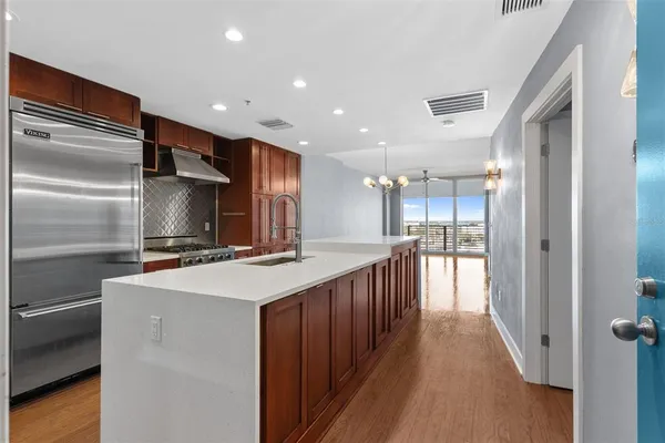 a kitchen with kitchen island a stove a refrigerator and a sink with wooden floor