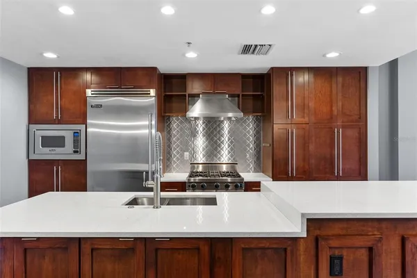 a kitchen with kitchen island a counter top space cabinets and stainless steel appliances