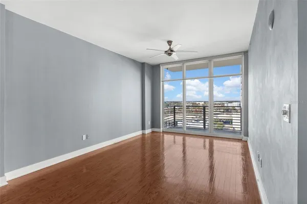 a view of an empty room with wooden floor and a window