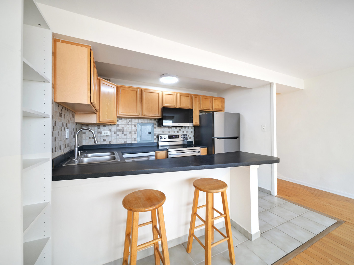 6030 North Sheridan Road, Unit 505 Chicago, IL 60660 - Photo 9 of 17 a kitchen with stainless steel appliances granite countertop a stove top oven a sink a dining table and chairs with wooden floor