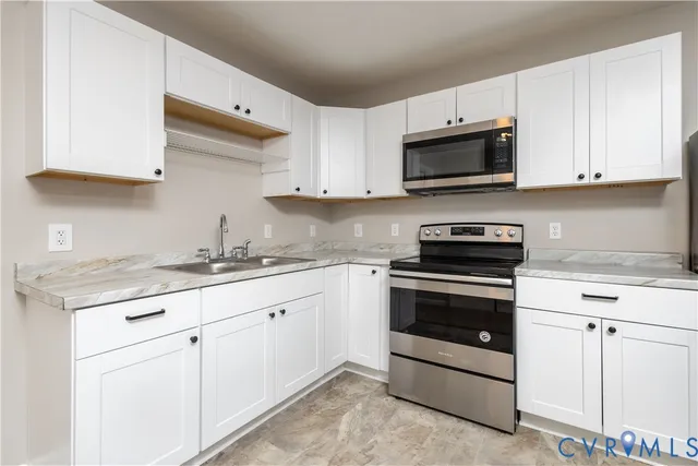 a kitchen with granite countertop white cabinets sink and stainless steel appliances