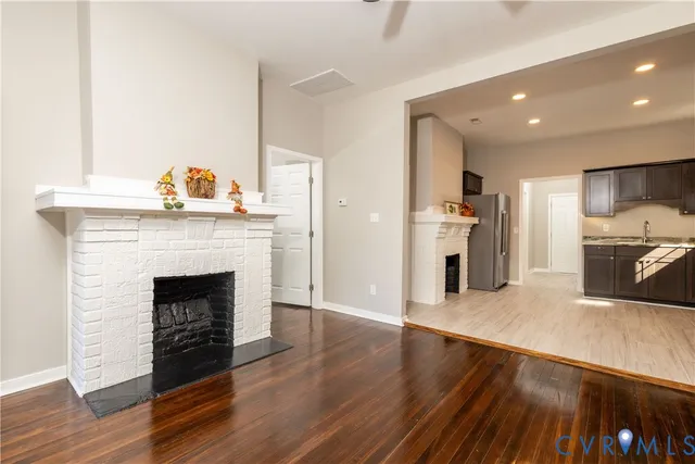 a living room with stainless steel appliances furniture a fireplace and wooden floor