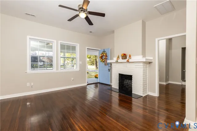 a view of a livingroom with a fireplace wooden floor and windows
