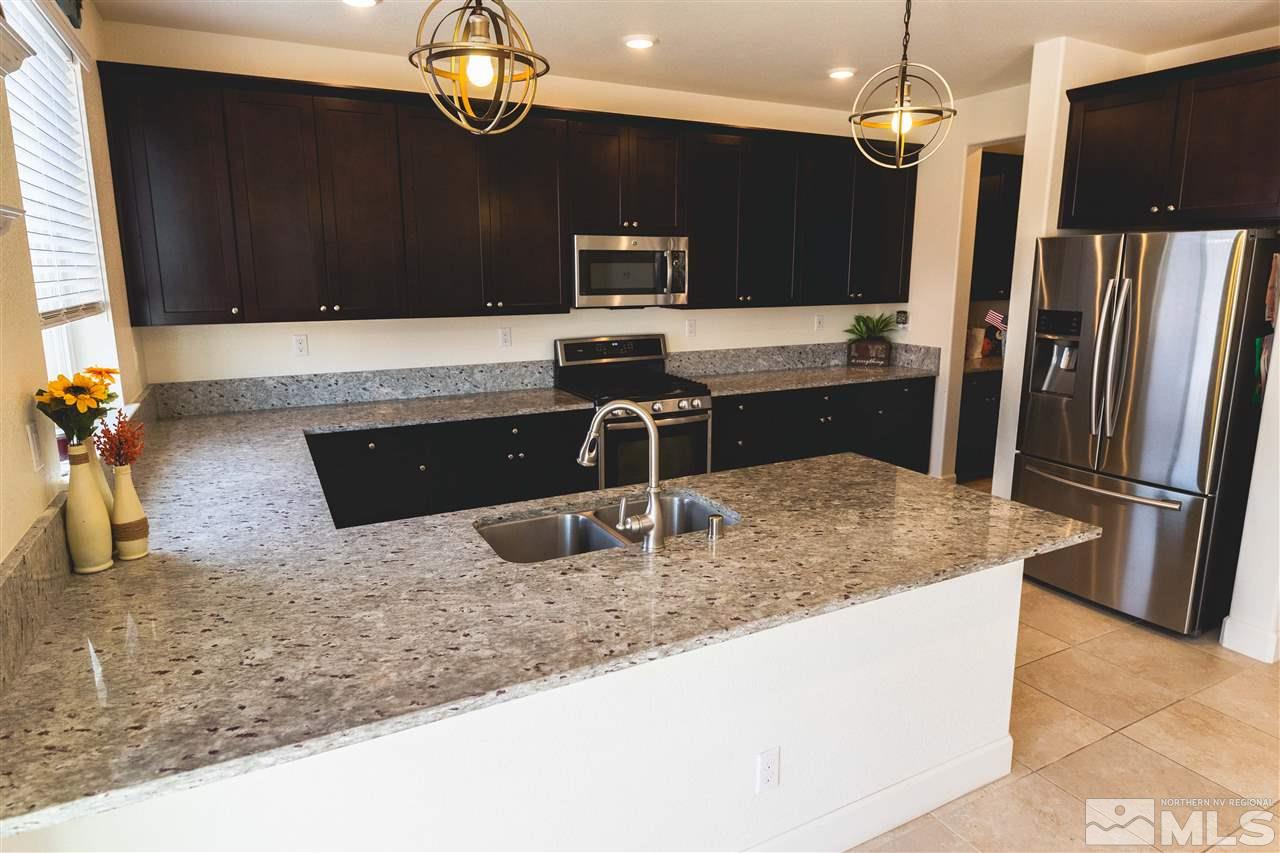 9746 Pachuca Drive Reno, NV 89521 - Photo 2 of 25 a kitchen with kitchen island granite countertop a sink refrigerator and microwave