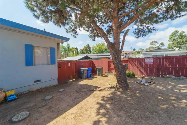 a view of backyard with wooden fence and large trees