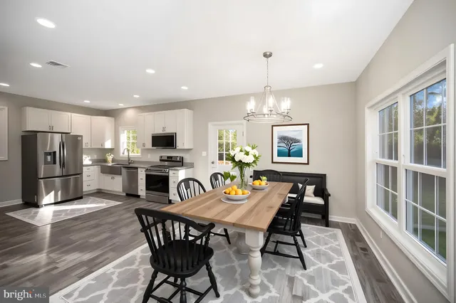 a view of a dining room with furniture a kitchen and chandelier