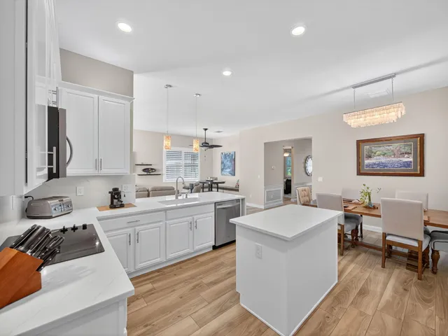 a large white kitchen with a stove a sink a dining table and chair
