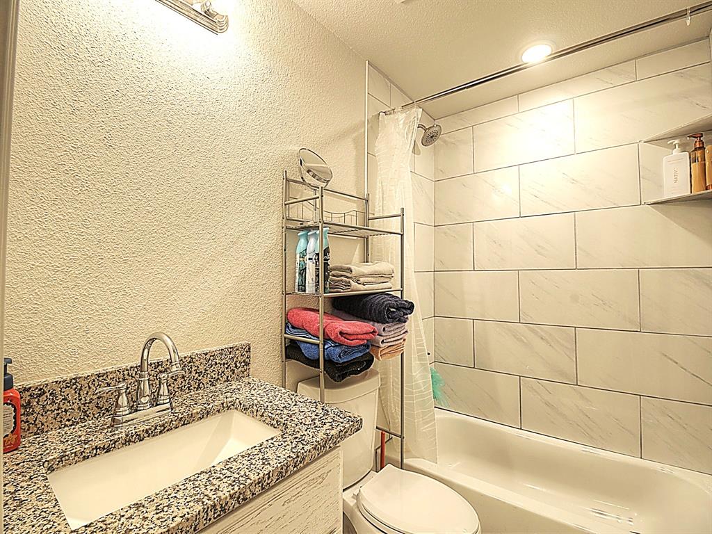 605 Olive Street Cleburne, TX 76031 - Photo 19 of 40 a bathroom with a granite countertop sink and a mirror