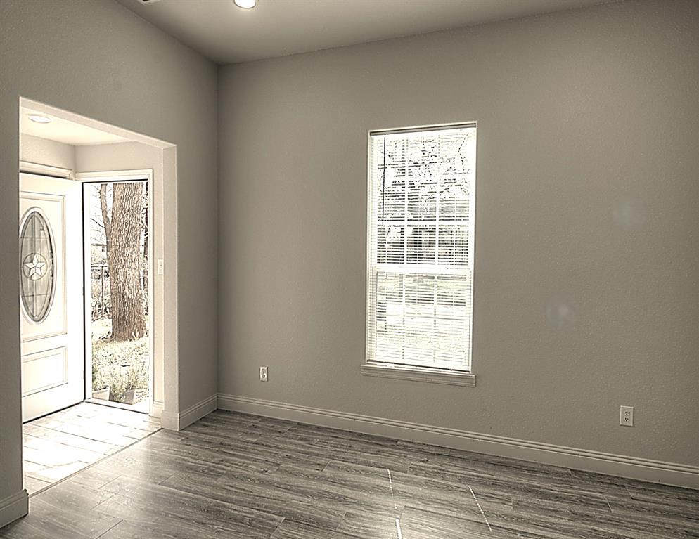 605 Olive Street Cleburne, TX 76031 - Photo 4 of 40 a view of an empty room with wooden floor and a window
