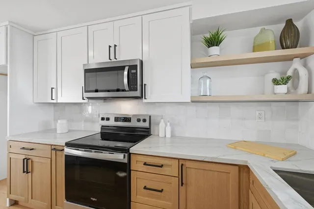 a kitchen with stainless steel appliances granite countertop a sink a stove and a microwave