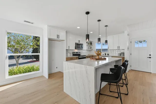 a kitchen with stainless steel appliances kitchen island a table chairs refrigerator and wooden floor