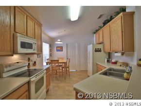 2032 Mango Tree Drive Edgewater, FL 32141 - Photo 9 of 24 a kitchen with stainless steel appliances granite countertop a sink a stove a dining table and chairs with wooden floor