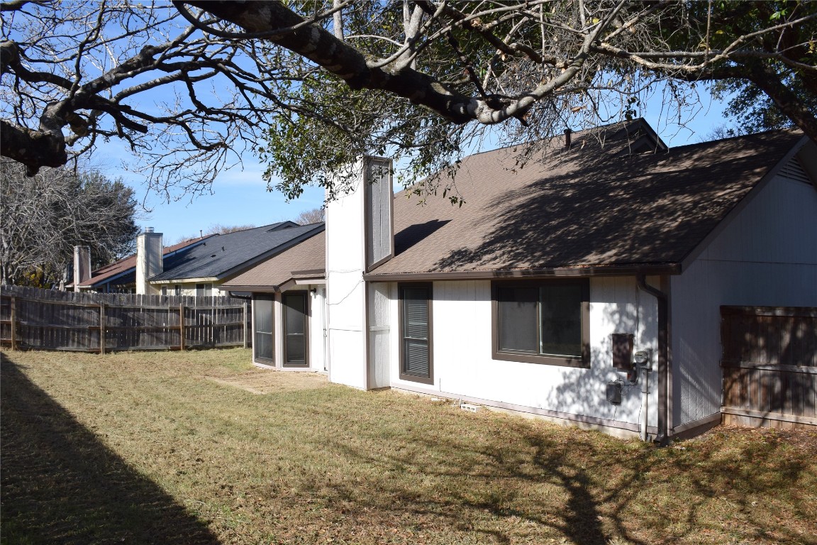 1911 Klattenhoff Drive Austin, TX 78728 - Photo 13 of 14 Rear view of house featuring a shingled roof and a chimney