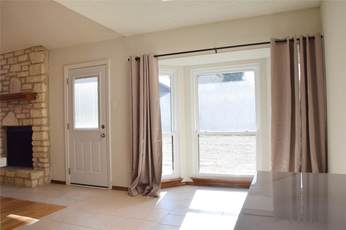 1911 Klattenhoff Drive Austin, TX 78728 - Photo 4 of 14 Doorway featuring a fireplace, tile patterned flooring, and a textured ceiling