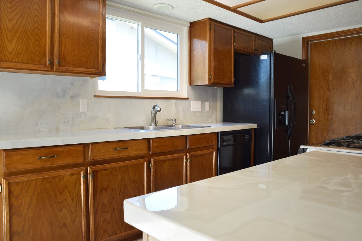 1911 Klattenhoff Drive Austin, TX 78728 - Photo 5 of 14 Kitchen featuring light countertops, brown cabinets, black appliances, and decorative backsplash