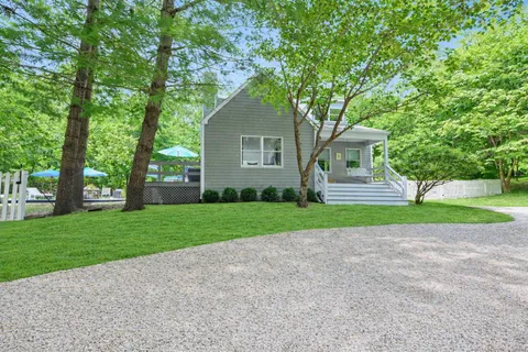 a view of a house with a yard and large trees