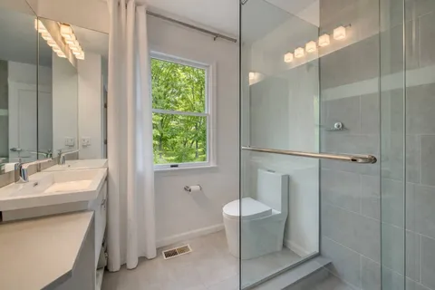a bathroom with a double vanity sink toilet and shower