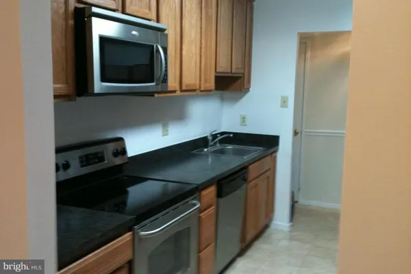 a kitchen with granite countertop stainless steel appliances a sink stove and microwave