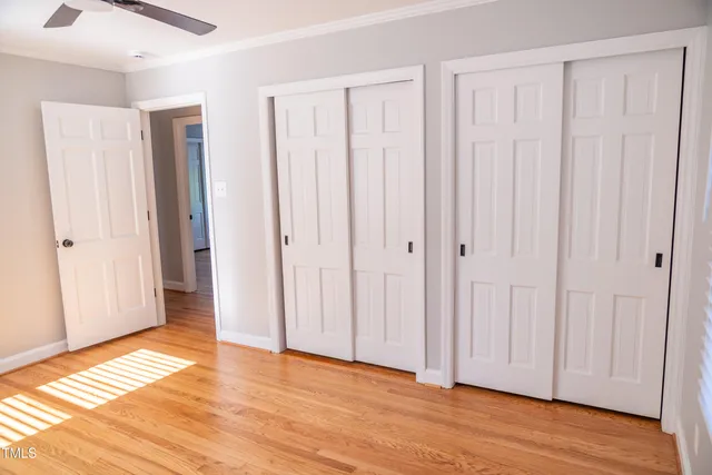 a view of empty room with wooden floor and fan