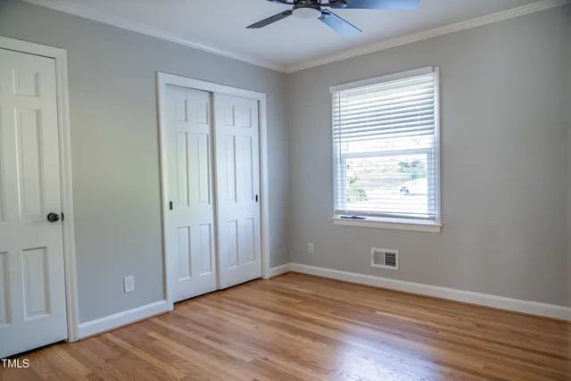 a view of an empty room with wooden floor and a window