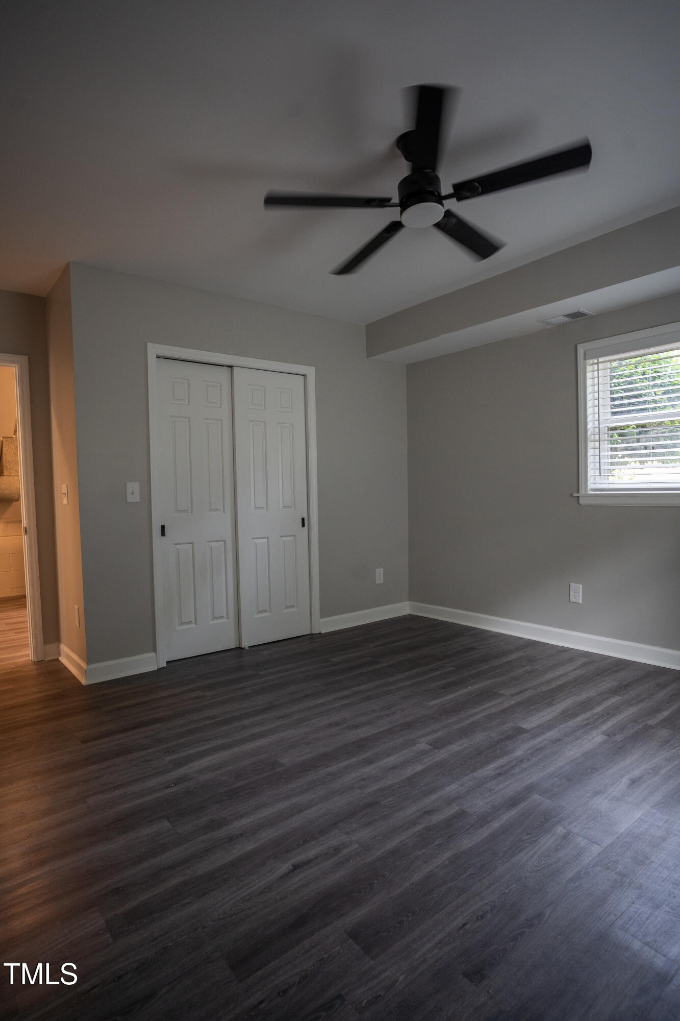 4813 Glen Forest Drive Raleigh, NC 27612 - Photo 33 of 39 a view of an empty room with wooden floor and a ceiling fan