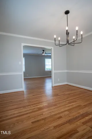 a view of empty room with wooden floor and ceiling fan
